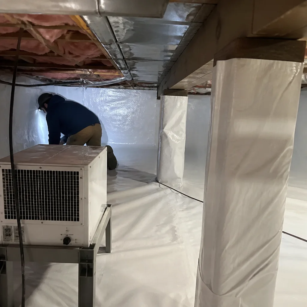 Contractor installing vapor barrier insulation in home crawl space
